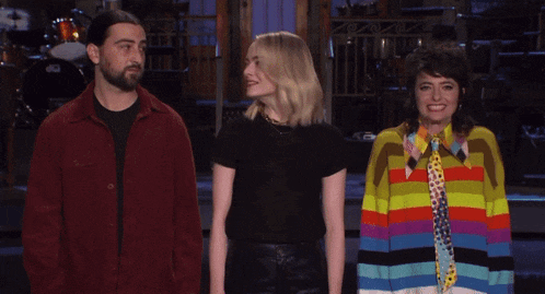 a man in a red jacket stands next to two women
