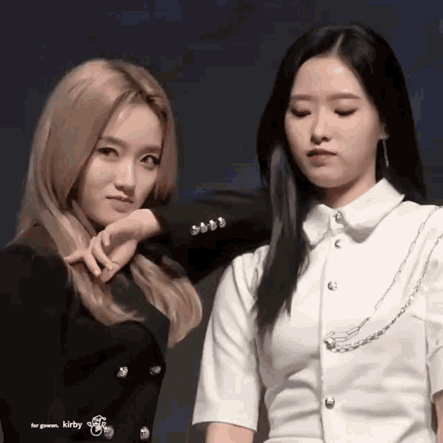 two girls are standing next to each other and one of them is holding the other 's arm .