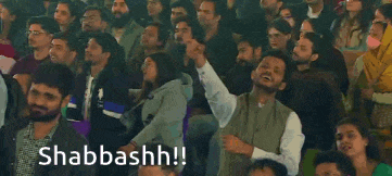 a crowd of people are sitting in a stadium with the words shabbashh written on the bottom .