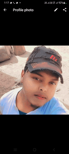 a young man wearing a black adidas hat takes a selfie on his phone