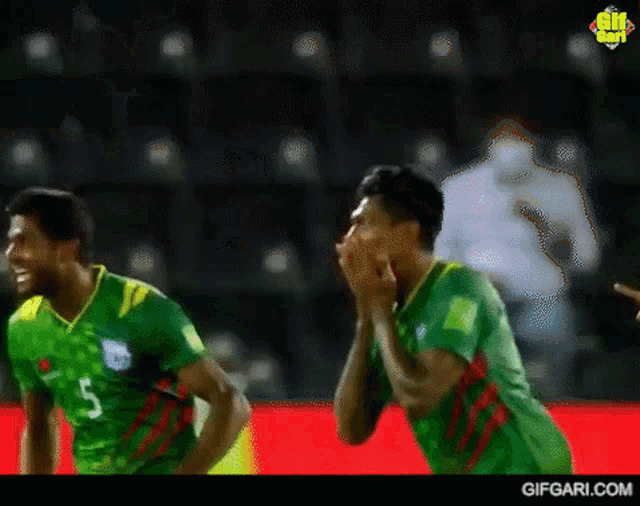 two soccer players wearing green jerseys with the number 5 on the front