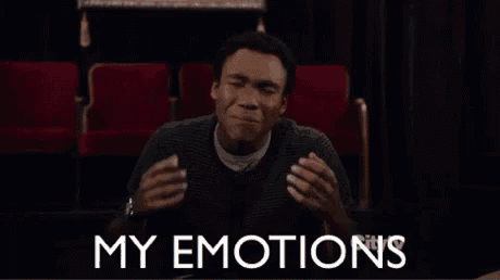 a man is sitting in a theater with his hands in his mouth and the words `` my emotions '' written on the screen .