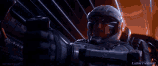 a man in a helmet is holding a gun and pointing it at the camera .