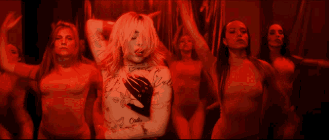 a woman with a tattoo on her chest stands in front of a group of dancers