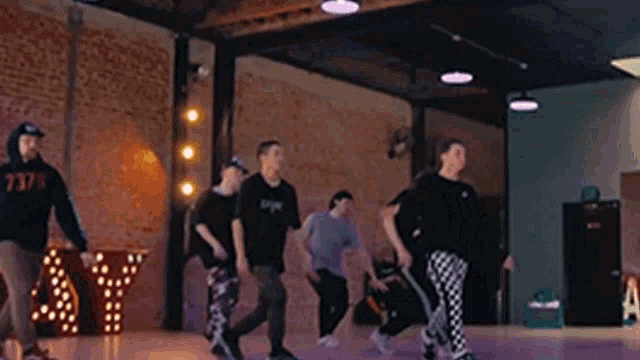 a group of people are dancing in a dance studio with a brick wall in the background .