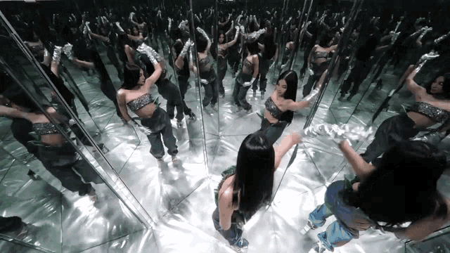 a woman is dancing in a mirrored room with many other women