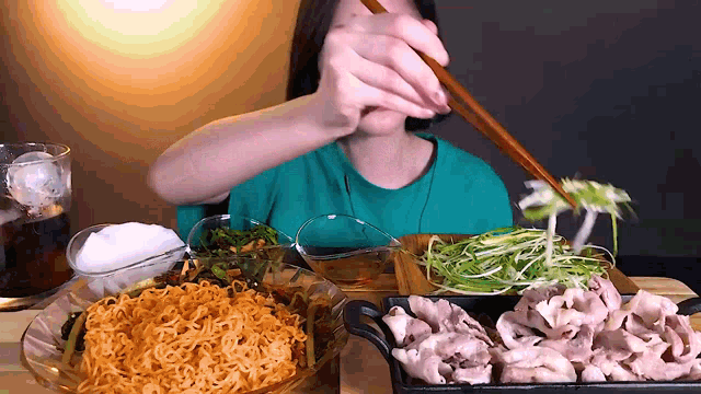 a woman is eating noodles with chopsticks from a bowl