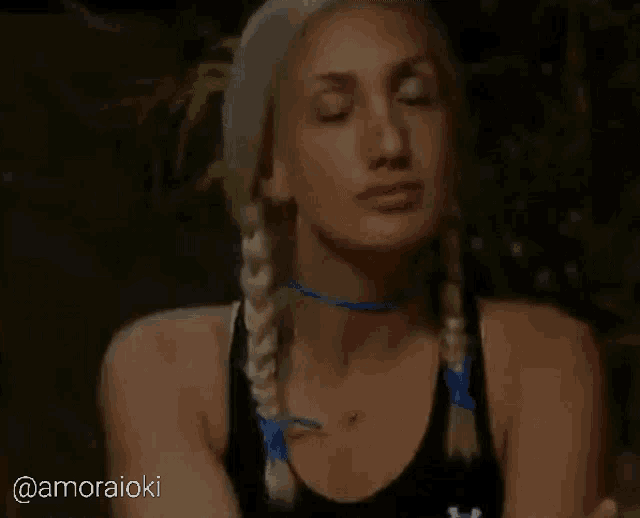a woman with blonde braids is wearing a black tank top with under armour written on it
