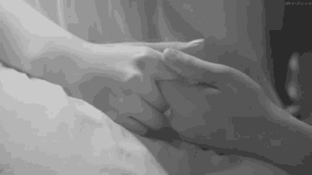 a black and white photo of a man and woman holding hands .
