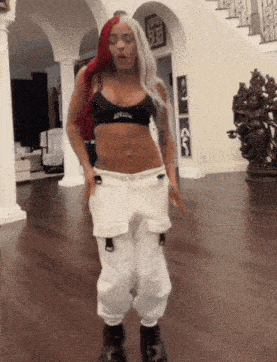 a woman with red and white hair is dancing in a room