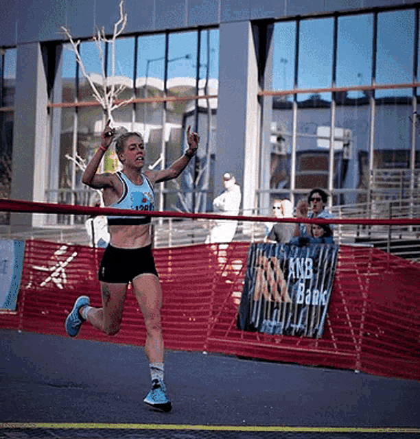 a runner crosses the finish line with a knb bank sign in the background