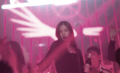 a woman is dancing in a club with a bottle of beer .