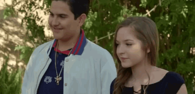 a boy and a girl are standing next to each other and smiling .