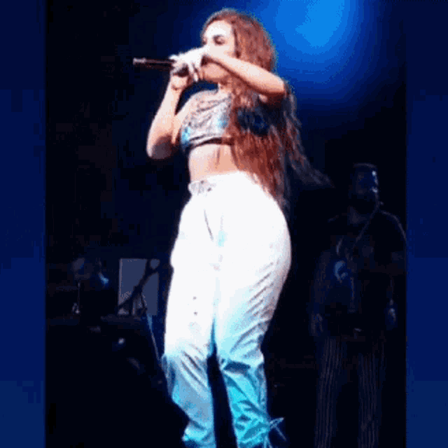 a woman is singing into a microphone on a stage in front of a band .