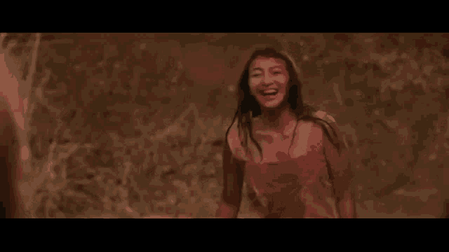 a woman with blood on her face is laughing while standing in a field .