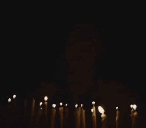 a man is blowing out a bunch of candles in the dark