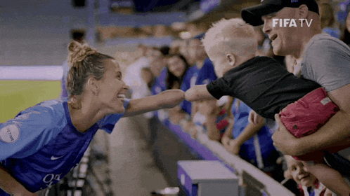 a woman in a blue nike jersey is holding a child
