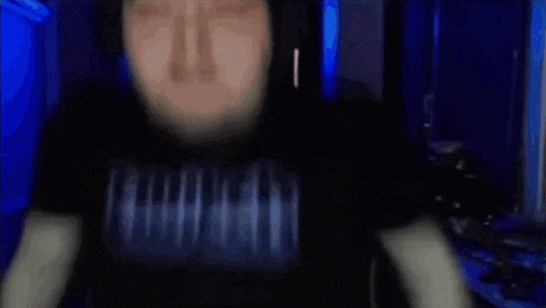 a man wearing a virtual reality headset is sitting in a dark room .