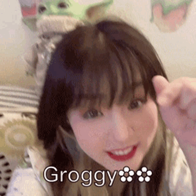 a girl is smiling and making a funny face with the word groggy on her face .