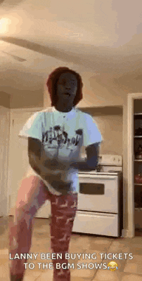 a man is dancing in a kitchen in front of a stove and a fridge .
