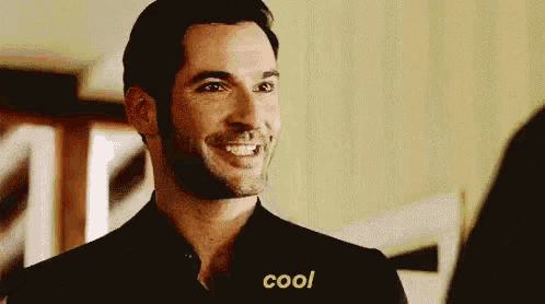 a man with a beard is smiling and saying `` cool '' while looking at another man .