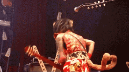 a blurred image of a person playing a guitar with the letter g on the back
