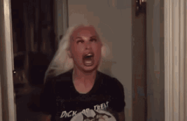 a woman with blonde hair is making a funny face in a doorway .