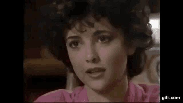 a close up of a woman 's face with a pink shirt on .