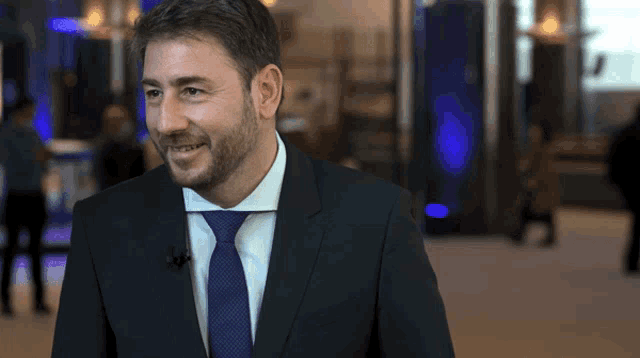 a man in a suit and tie is smiling in a room