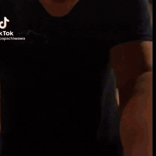 a man in a black shirt and black pants is standing in a room .