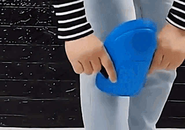a person in a striped shirt is holding a blue object in their hands .