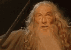 a man with a beard and long hair is standing in a dark room .