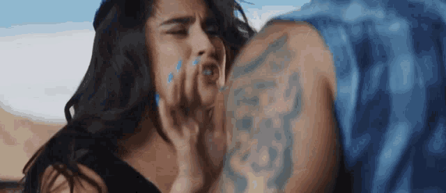 a man with a tattoo on his arm is kissing a woman 's face .