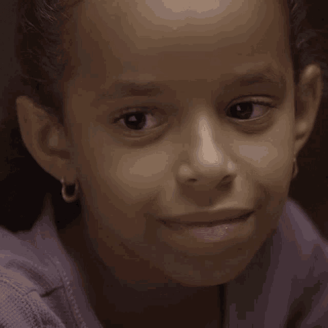 a close up of a young girl 's face with a purple shirt on