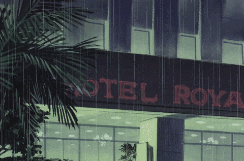 a hotel royal sign is lit up in red in the rain