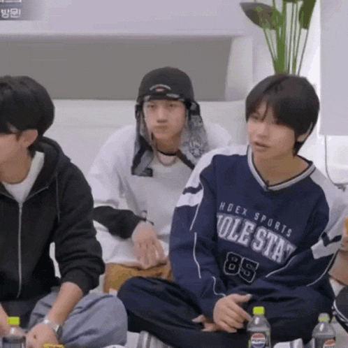 a group of young men are sitting on a couch and one of them is wearing a sweatshirt that says hoex sports