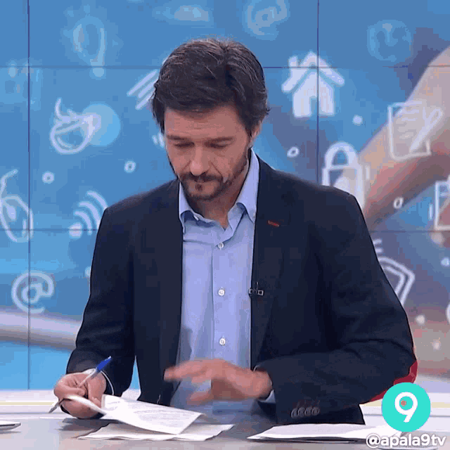 a man in a suit is writing on a piece of paper in front of a wall with icons on it