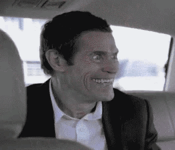 a man in a suit and white shirt is smiling in the back seat of a car