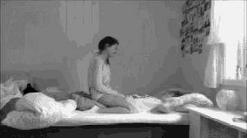 a black and white photo of a woman sitting on a bed next to a man .