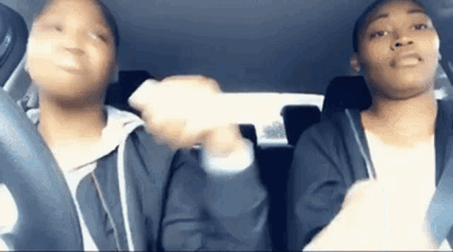 two girls are sitting in the back seat of a car and holding hands .