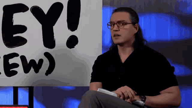 a man sitting in front of a sign that says " ey "