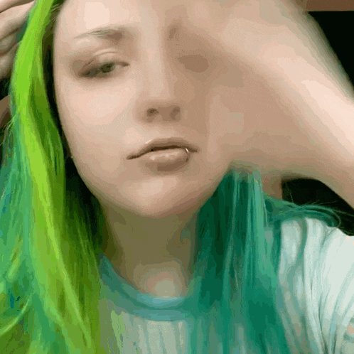 a woman with green hair and a nose ring looks at the camera
