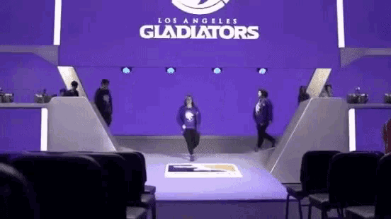 a woman is walking on a stage in front of a los angeles gladiators logo