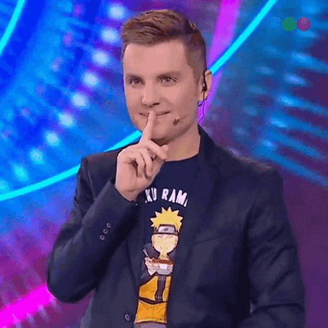 a man in a suit and a naruto shirt is making a shhh gesture