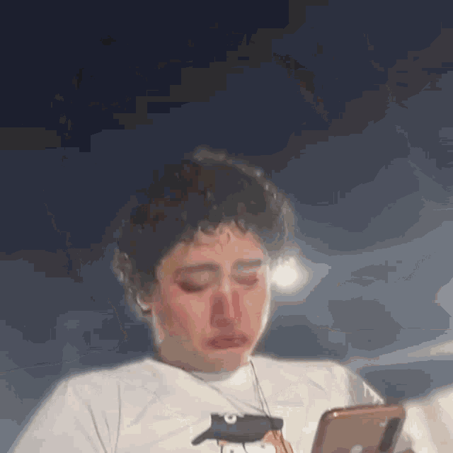 a young woman is crying while looking at her phone .