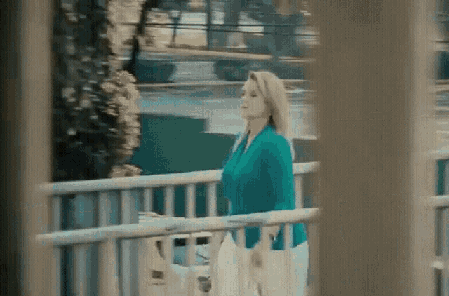 a woman in a blue sweater is walking across a bridge