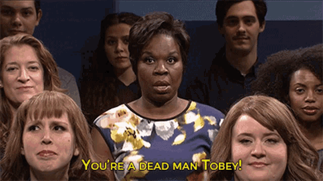 a woman stands in front of a crowd of people and says you 're a dead man tobey