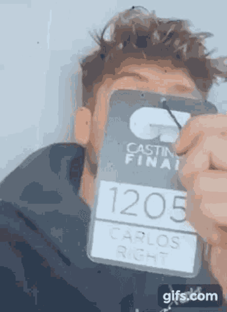 a man is holding a badge that says carlos right .