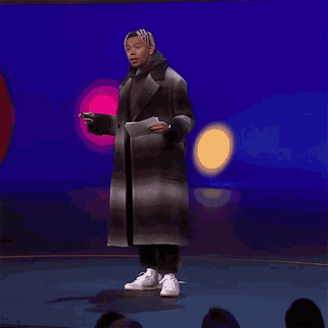 a man in a plaid coat stands on a stage holding a piece of paper and says that did n't happen