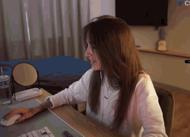 a woman sits at a desk in front of a monitor that says ' c ' on it